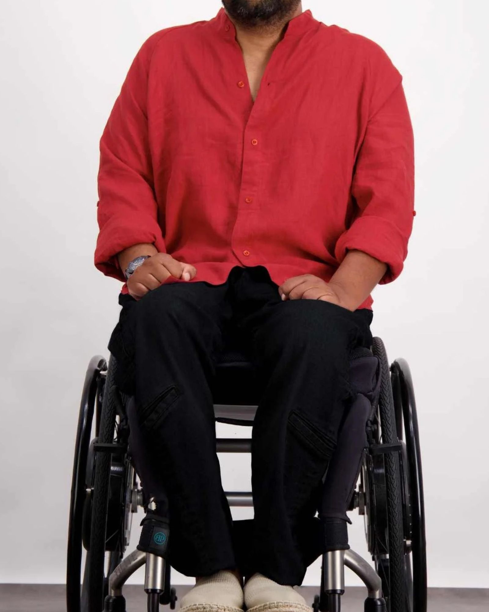 Cruiser Magnetic Linen Shirt shown in vibrant red, featuring a mandarin collar and rolled sleeves, styled with black pants. The adaptive shirt demonstrates its accessible design while seated in a wheelchair, highlighting the magnetic closure system for easy dressing.