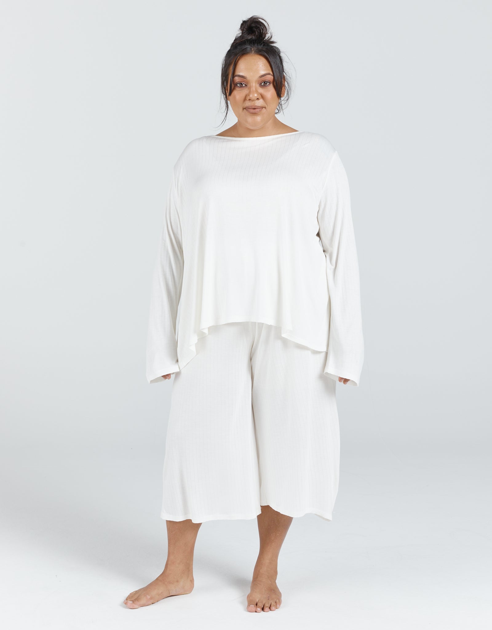 The Essensual PJ Set features a flowy white two-piece sleepwear ensemble with a loose-fitting long-sleeve top and cropped wide-leg pants, photographed against a light gray background, showcasing comfortable adaptive sleepwear design and relaxed silhouette.