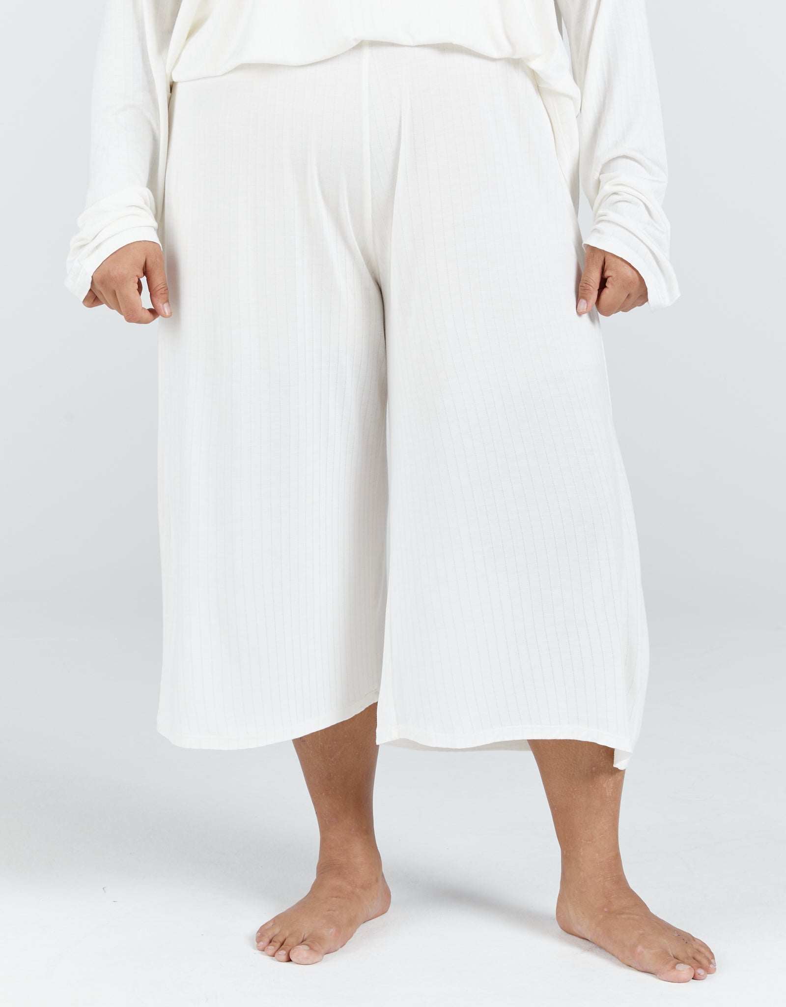 The Essensual PJ Set features comfortable wide-leg cropped pants in crisp white, showcasing a relaxed fit and flowing silhouette perfect for lounging. The sleepwear bottoms are shown against a light background, highlighting their elegant simplicity and premium comfort design.