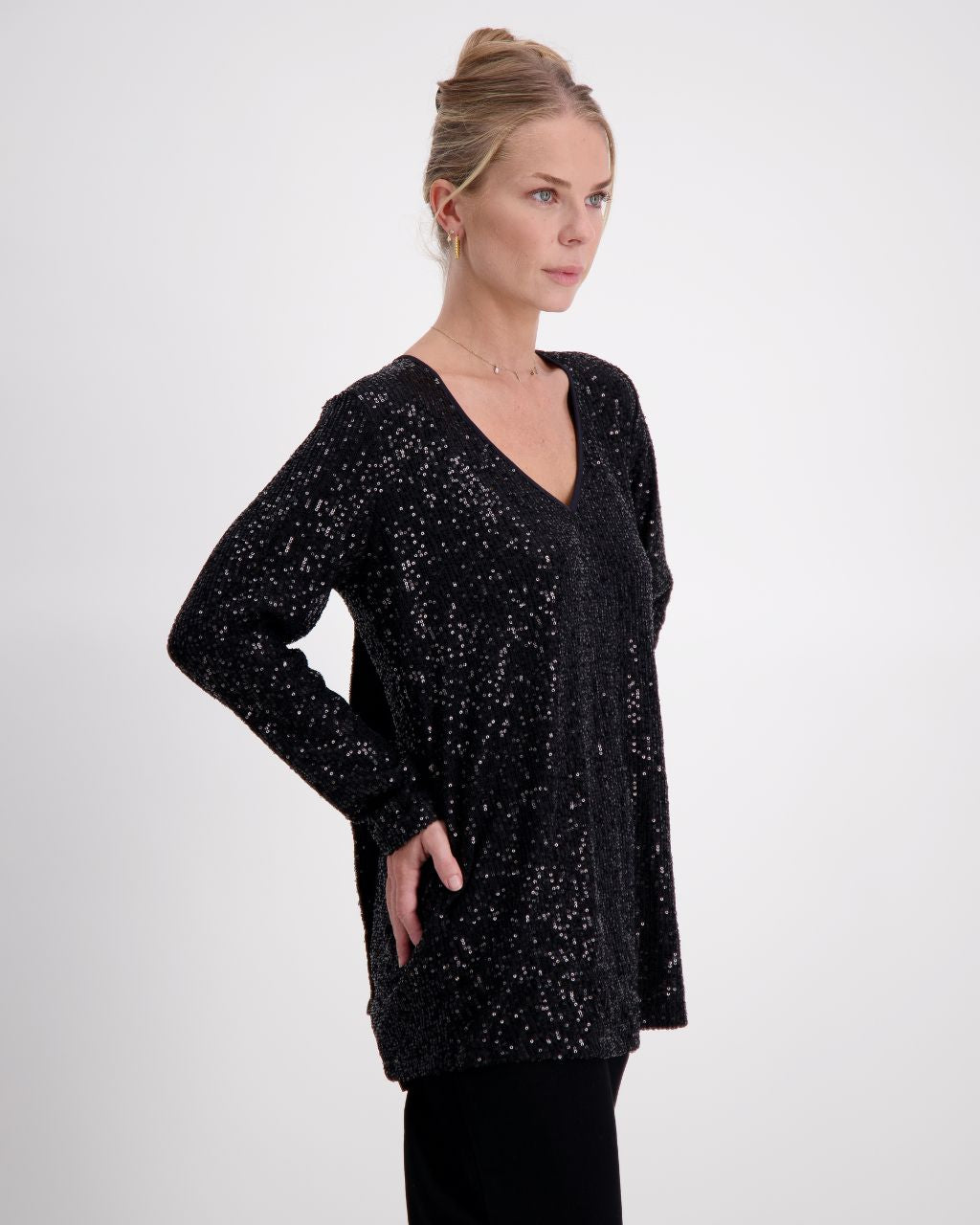 Tara V Neck Leaf Back Top in shimmering black metallic glitter fabric featuring a plunging V-neckline and full-length sleeves. The elegant design showcases a signature leaf pattern on the back, perfect for evening wear.