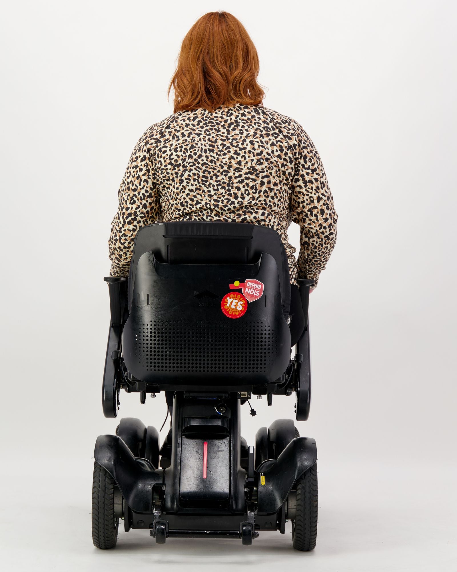 Back view of the Maggie Thermal Top in leopard print pattern, shown on a person seated in a mobility device, demonstrating the adaptive design and comfortable fit for wheelchair users