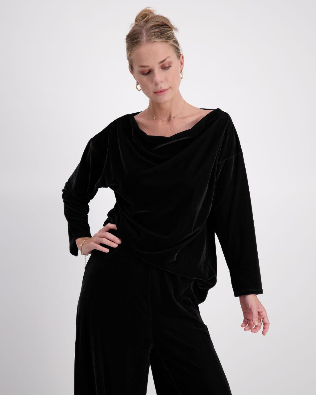 Emma Boat Neck Leaf Back Top in luxurious black velvet, featuring an elegant boat neckline, three-quarter length sleeves with split cuffs, and a distinctive leaf-back design. The top is shown styled against a light background, highlighting the plush texture and sophisticated draping.