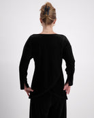 Emma Boat Neck Leaf Back Top shown from behind, featuring luxurious black velvet fabric with distinctive overlapping leaf design at back. Three-quarter length sleeves with split cuffs, showcasing elegant draping and sophisticated tailoring against neutral background.