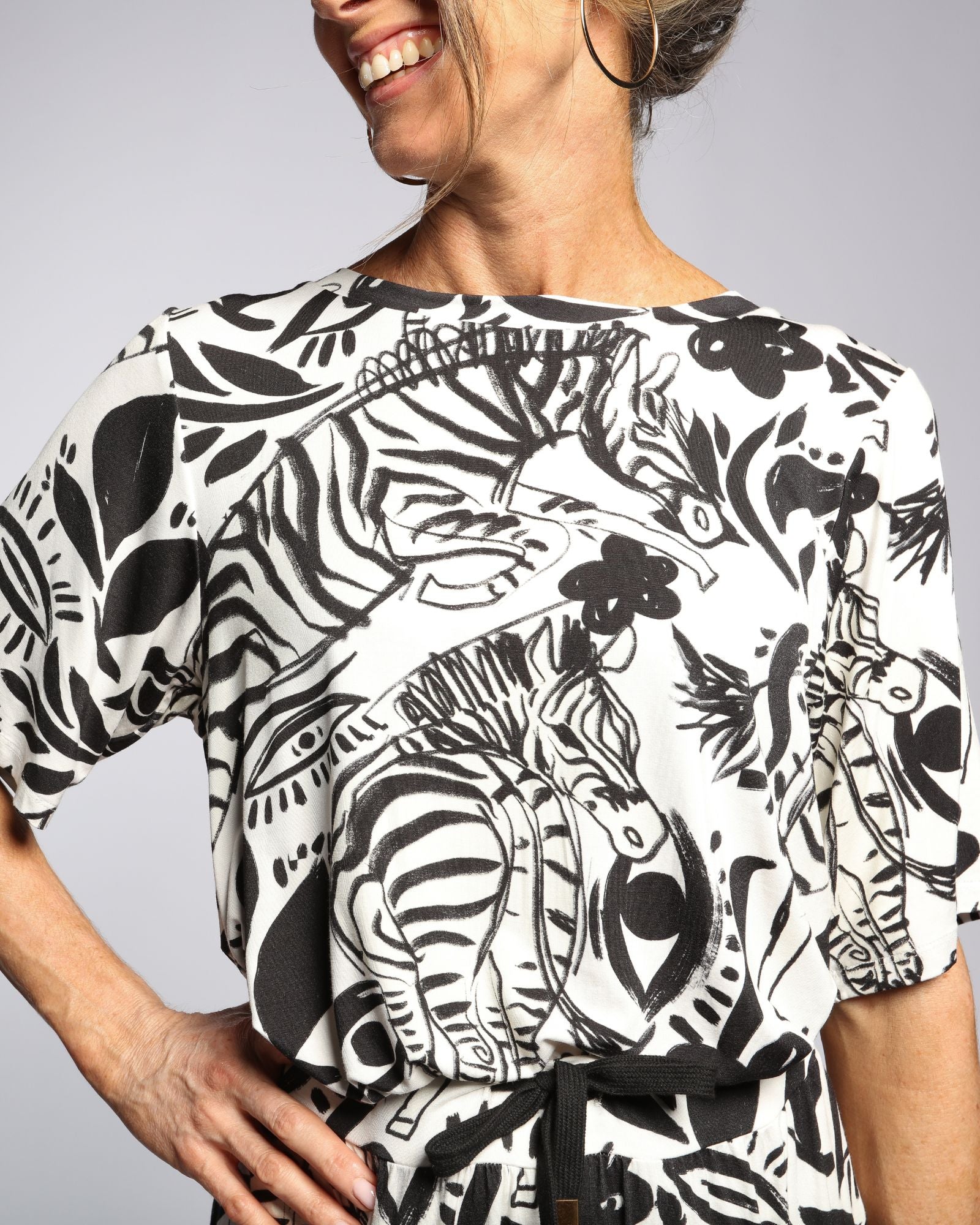 Lilli Leaf Back T-Shirt featuring a striking black and white abstract floral and zebra print pattern on sensory-friendly bamboo fabric, showcasing loose-fit elbow-length sleeves and a relaxed neckline. Side view displays the artistic print detail against a light gray background.