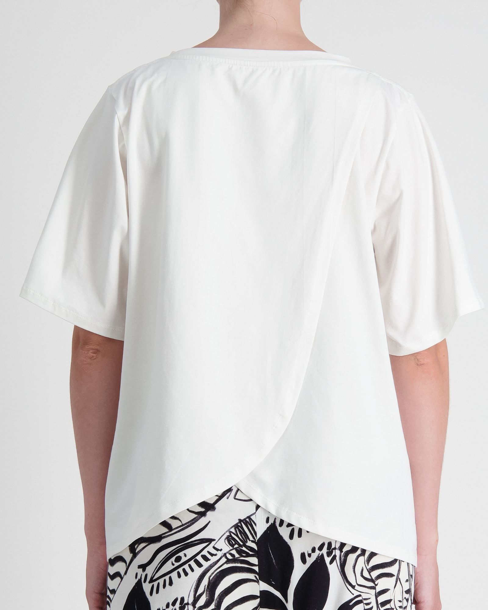 Lilli Leaf Back T-Shirt featuring a back view of a white adaptive shirt with overlapping panels, showcasing innovative StainFree technology. The short-sleeved design displays clean lines and a comfortable fit against a light gray background.