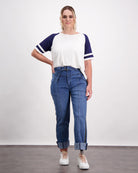 Lisa Raglan Leaf Back T-Shirt styled with blue jeans, featuring white body with navy blue sleeves and white stripes, casual athletic design against light background, tucked into high-waisted denim with rolled cuffs and paired with white sneakers