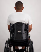 Back view of Nick A-Line T-Shirt in white bamboo fabric, shown on a person seated in a black wheelchair. The adaptive t-shirt demonstrates a comfortable, relaxed fit with clean lines and stretchy material suitable for everyday wear.