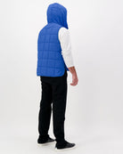 Matt Gender Neutral Puffer Vest shown from back view in vibrant royal blue, featuring quilted design, hood, and white long-sleeve underlayer. The vest displays adaptive design elements, showcasing lightweight construction and practical functionality against a clean white background.