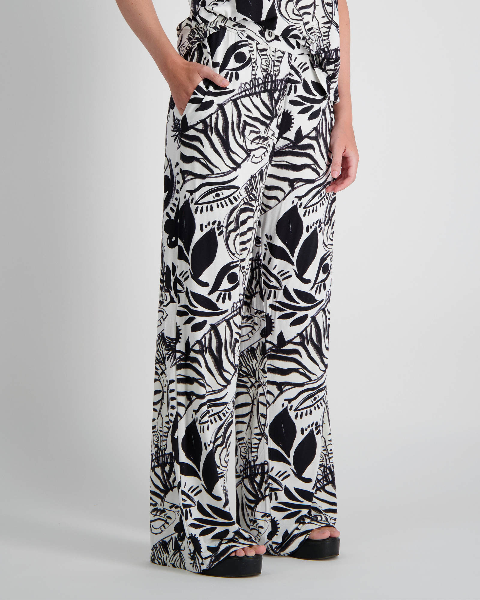 Jessie Wide Leg Pant showcasing a bold black and white abstract botanical and zebra print pattern on flowing wide-leg silhouette. Features side pockets and relaxed fit, made from bamboo and linen blend fabric for adaptive comfort.