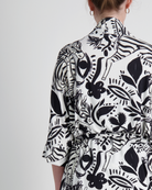 Back view of the Georgie Adaptive Kimono featuring a striking black and white botanical print pattern, showcasing wide sleeves and seamless design on a light background. The cropped style displays modern, bold floral and leaf motifs with artistic line work.