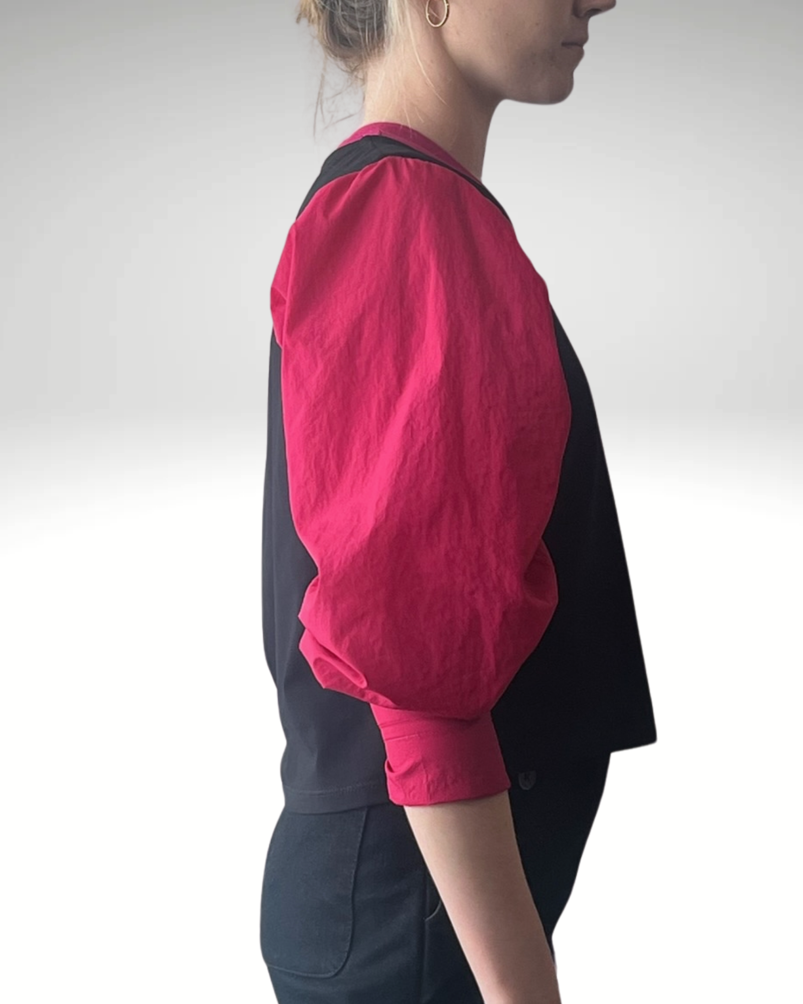 Wicky Smart-Tech Vest shown from side profile featuring black body with contrasting vibrant raspberry-colored sleeves, demonstrating its modern silhouette and adaptive design. Professional studio lighting highlights the stain-resistant fabric texture and sleek side-zip details.