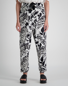 Roisin Adaptive Slouch Pants showcased in striking black and white botanical print on bamboo fabric, featuring tapered legs, drawstring waist, and relaxed fit. Styled with black platform sandals against light grey background.