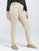 Seated Stretch Pant shown in beige color, paired with black top and tan sandals, featuring adaptive design with higher back rise and well-fitted leg length. Side view displays smooth fit and tailored silhouette against light background.