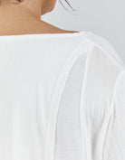 Close-up view of Essensual PJ Top in white, showing delicate ribbed texture and shoulder detail with elegant draping fabric. Features a soft, breathable material with refined stitching visible along the neckline and shoulder seam.