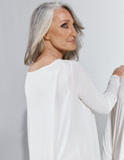 Side view of the Essensual PJ Dress in pure white featuring long sleeves and a relaxed fit, showcasing the elegant drape of the soft fabric against a light gray background, perfect for comfortable nighttime wear