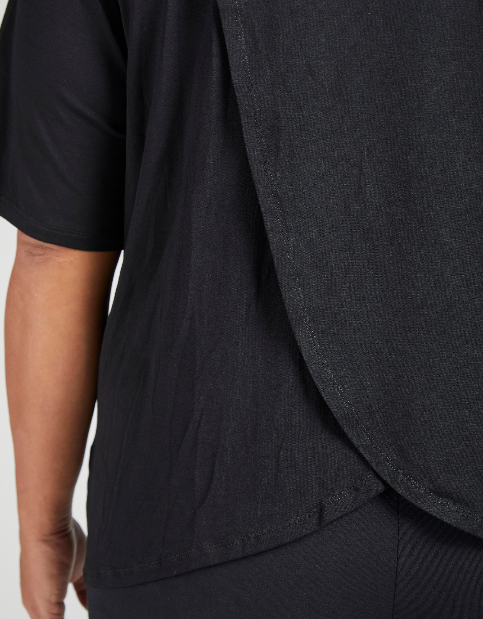 Short Sleeve Leaf Back T-Shirt featuring a stylish black design with curved hem detail and elegant draping at the back, showcasing a modern silhouette and premium fabric quality