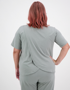 Back view of Short Sleeve Leaf Back T-Shirt in sage green, featuring unique overlapping fabric design at the back, showcasing its distinctive leaf-inspired silhouette against a white background. The t-shirt demonstrates a relaxed, comfortable fit with clean lines and elegant draping.